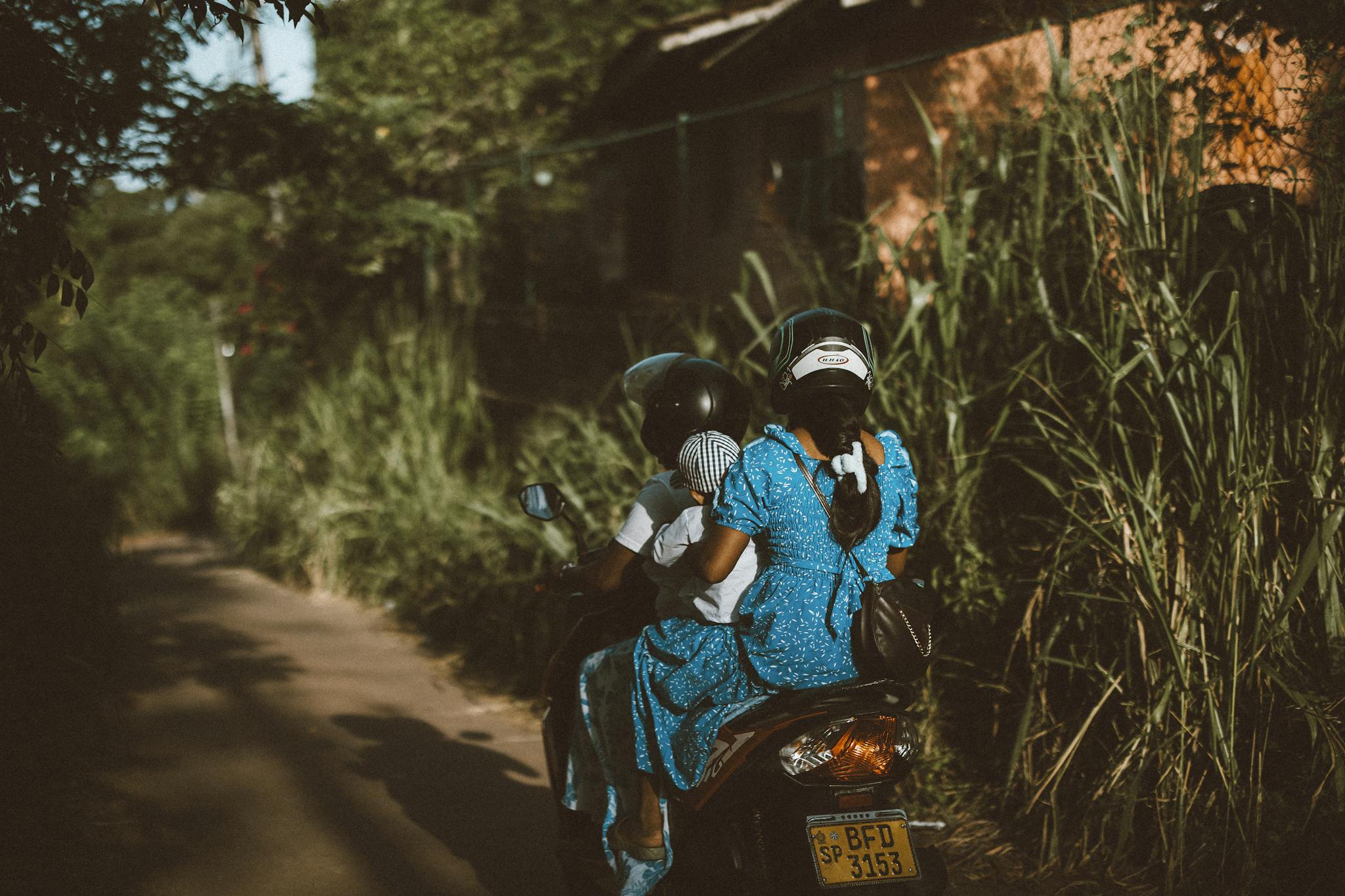 A family riding a motorcycle through lush greenery in Sri Lanka, showcasing travel and lifestyle.