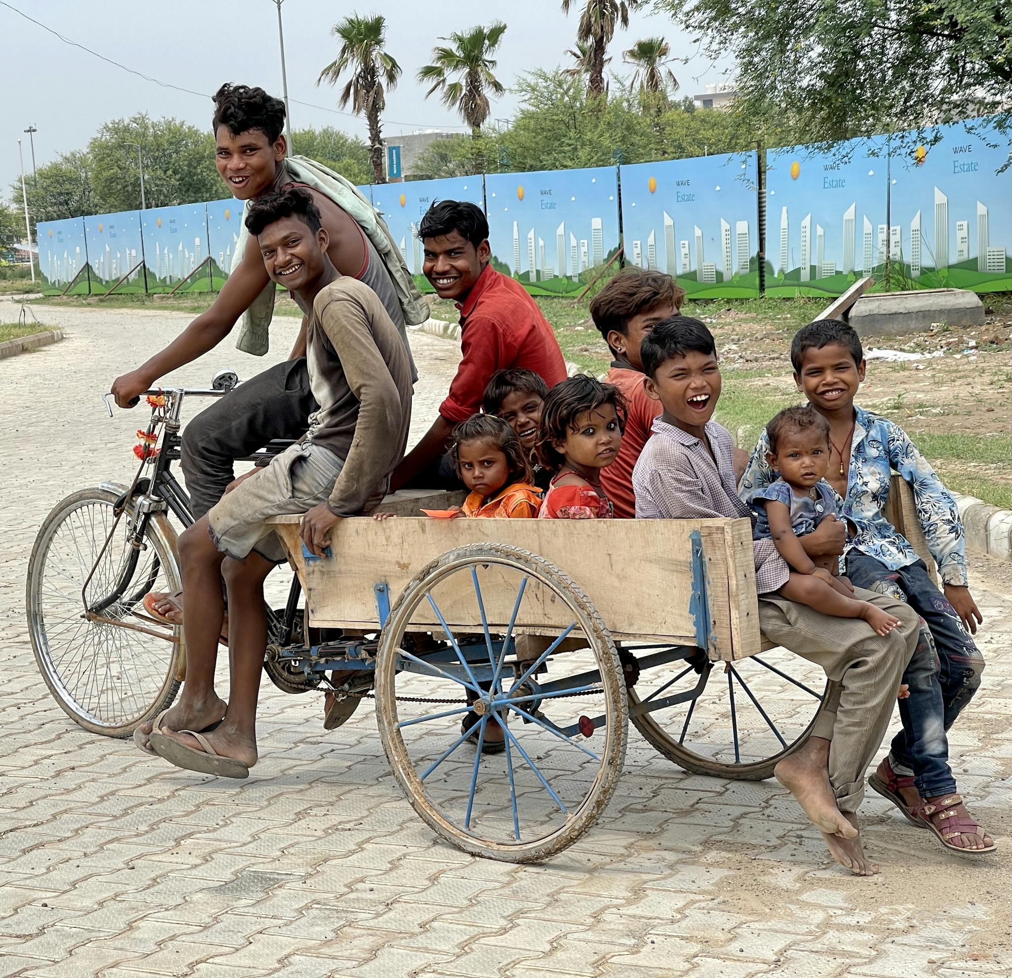 A group of children enjoying a ride on a tricycle cart outdoors in India, embodying joy and playfulness.