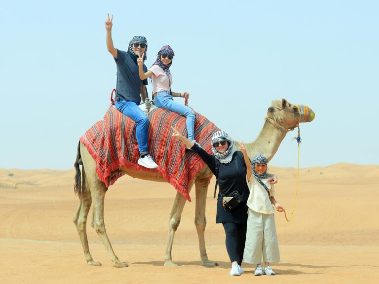 A joyful family posing with a camel in the Dubai desert, capturing the essence of adventure.