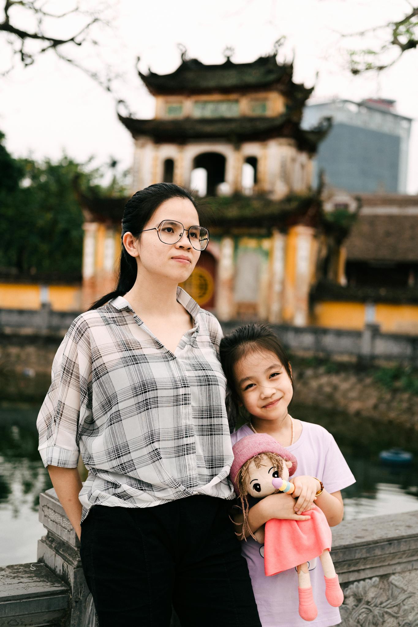 A mother and daughter pose by a historic temple, showcasing family bonding and cultural heritage.